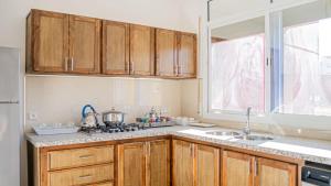 a kitchen with wooden cabinets and a sink and a window at Airport Apartment M&A in Nador +4 photos