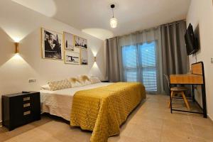 ein Schlafzimmer mit einem Bett mit einer gelben Decke und einem Schreibtisch in der Unterkunft El Castillo Golf Salinas-wifi in La Guirra