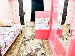 een roze kamer met 2 bedden en een spiegel bij شقة مميزة بجوار كورنيش النيل اسوان - عائلات فقط in Aswan