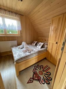 een kamer met een bed in een houten hut bij Domek pod lasem in Klikuszowa