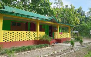 a yellow and red house with a green roof at Leo Jungle Retreat by StayApart , Jaldapara in Mādāri Hāt