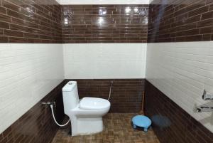 La salle de bains est pourvue de toilettes blanches et d'un tabouret bleu. dans l'établissement Hotel Kaushalya Residency Inn Uttarakhand Near By Gandhi Park - Family-friendly, à Berināg