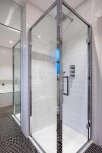 a glass shower in a bathroom with white tiles at Veeve - A Vision in Blue in London