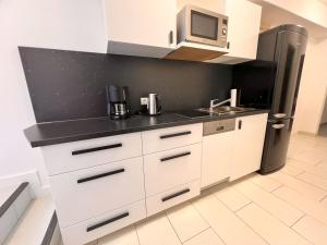 eine Küche mit weißen Schränken und einem schwarzen Kühlschrank in der Unterkunft db-rooms-i in Kassel