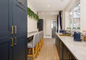 a kitchen with blue cabinets and a counter with chairs at The Milton sleeps 8 close to York city centre pet friendly in York