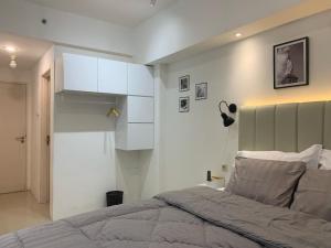 a bedroom with a bed and a white wall at Pakuwon Mall Dovey Apartment in Surabaya