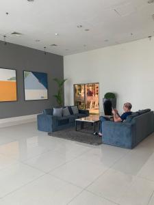 a man sitting on a couch in a living room at Pakuwon Mall Dovey Apartment in Surabaya