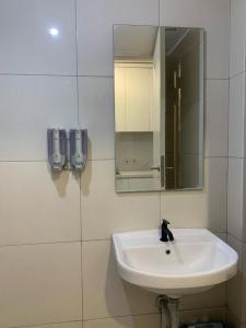a white bathroom with a sink and a mirror at Pakuwon Mall Dovey Apartment in Surabaya
