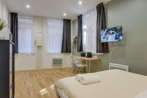 a bedroom with a bed and a table and windows at Lille Centre - Nice studio in Lille