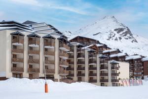 a building in the snow with a mountain in the background at Résidence Le Machu Pichu in Val Thorens