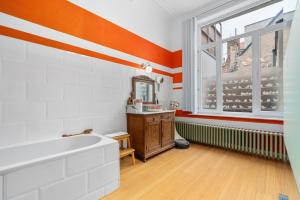 een oranje en witte badkamer met een bad en een raam bij Karaktervolle en ruime woning aan zee voor 10p in Oostende