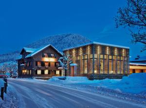 un gran edificio en la nieve por la noche en Genießer - & Romantik Hotel DAS SCHIFF en Hittisau