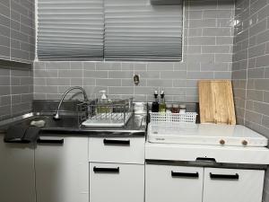 a kitchen with white cabinets and a sink and a counter at Nroo Stay in Seoul