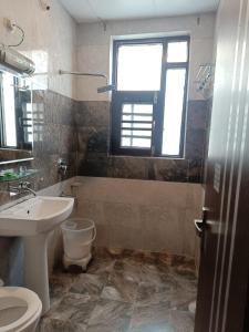 baño con lavabo y aseo y ventana en The Hotel Influence, en Pahalgām