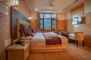 1 dormitorio con cama, escritorio y ventana en The Hotel Influence, en Pahalgām