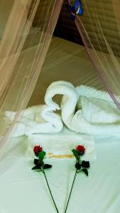 a towel and two roses on a bed at Dreamer Resort in San Vicente
