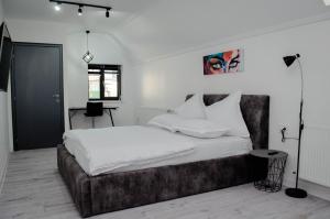 een slaapkamer met een groot bed met witte lakens bij PentGarden penthouse jacuzzi in Târgu Jiu