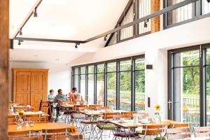 people sitting at tables in a restaurant with large windows at Landhotel - Hotel & Brauereigasthof Schneider in Essing