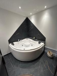 La salle de bains est pourvue d'une grande baignoire blanche et d'un mur noir. dans l'établissement Château Le Fournel, à La Fouillouse