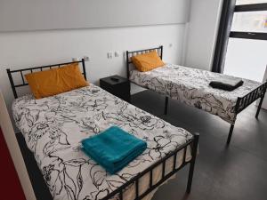 2 camas en una habitación con una almohada verde en Hostal NANA B&B en Arroyo de la Encomienda