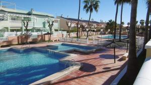 een zwembad in een resort met 2 zwembaden en palmbomen bij Gran Alicante Bungalow in Beach Resort in Puerto Marino