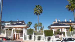 een wit hek voor een huis met palmbomen bij Gran Alicante Bungalow in Beach Resort in Puerto Marino
