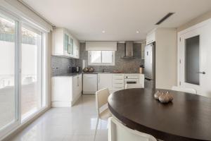 a kitchen with a wooden table and white cabinets at Buccara Altea Beach Villas in Altea