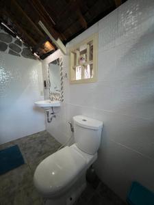 a white bathroom with a toilet and a sink at Lunazul Guesthouse in San Vicente