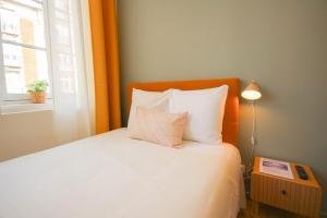 um quarto com uma cama branca com um candeeiro e uma janela em Lille Grand Place - Nice and equipped studio! em Lille