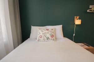 un letto bianco con un cuscino e una parete verde di Lille Grand Place - Nice and equipped studio! a Lille Altre 30 foto