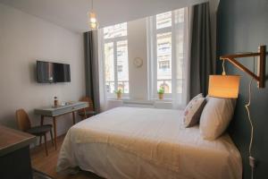 una camera da letto con un letto, una scrivania e finestre di Lille Grand Place - Nice and equipped studio! a Lille