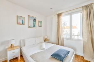 een witte slaapkamer met een bed en een raam bij Superbe appartement terrasse 75m Paris in Saint-Mandé