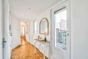 a white hallway with a mirror and a table at Superbe appartement terrasse 75m Paris in Saint-Mandé +11 photos
