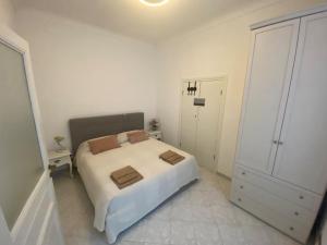 een witte slaapkamer met een bed en een kast bij La Casa di Gill in Sanremo
