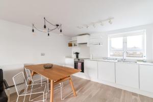 une cuisine avec des placards blancs et une table en bois dans l'établissement Belgravia Apartment 22, à Londres