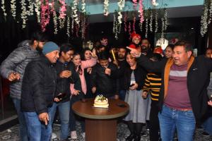 a group of people standing around a table with a cake at Yellow Leaf in Rishīkesh