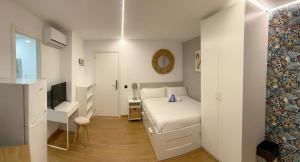 a small white bedroom with a bed and a television at Modular Suites Alfonso Gómez in Madrid