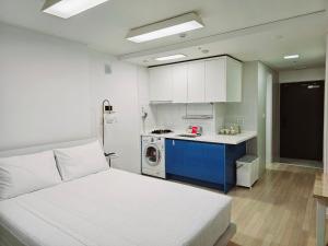 sypialnia z białym łóżkiem i kuchnią w obiekcie Jeoung's House w Pusanie