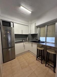 cocina con armarios blancos y nevera de acero inoxidable en Затишна квартира Playa Levante, en Santa Pola
