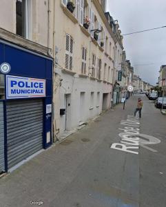 une personne marchant dans une rue à côté d'un bâtiment dans l'établissement La Fabrique Cherbourgeoise - Les Loges Normandes, à Cherbourg en Cotentin