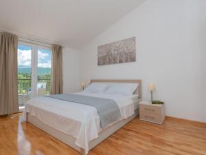 a white bedroom with a bed and a large window at Villa Drazana in Imotski