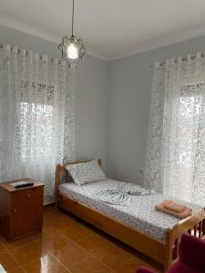 a bedroom with a bed with curtains and a table at Eiffel's Guest House in Pogradec