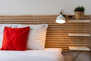 里爾的住宿－Vieux Lille appartement 1 chambre，床上的红色枕头,带有木制床头板