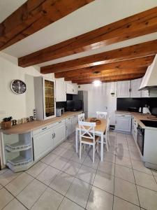 uma cozinha com armários brancos e uma mesa e cadeiras em La Fermette Aux Lamas em Savigny-Lévescault