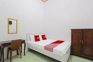 sypialnia z łóżkiem z czerwonymi poduszkami i biurkiem w obiekcie OYO 91817 Hotel Grand New Si Jago w mieście Kebumen
