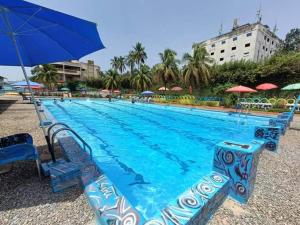 a large blue swimming pool with chairs and an umbrella at NS Immo Yaounde Cameroun in Yaoundé