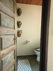 a door to a bathroom with a toilet and masks on the wall at Busua Beach House in Busua