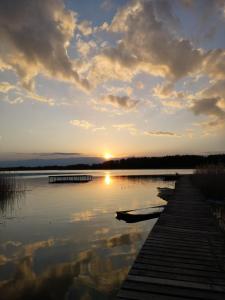 a sunset over a lake with a wooden dock at Domki pod mazurskim niebem in Pilchy