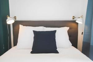 1 cama con almohada blanca y negra y 2 luces en Superb apartment near the Grand Place!, en Lille