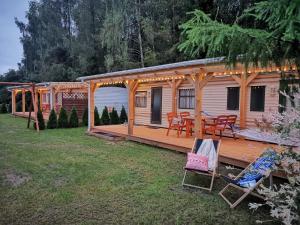 a wooden cabin with a deck with a table and chairs at Domki pod mazurskim niebem in Pilchy